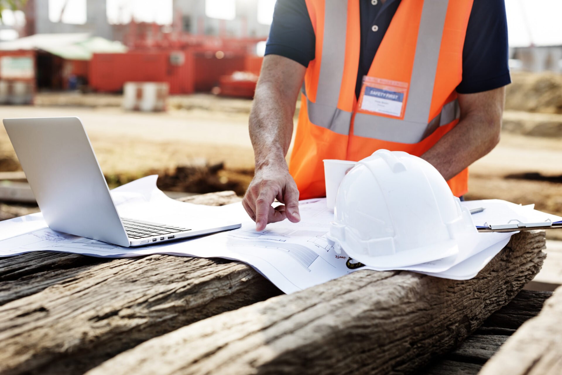 closeup-of-contractor-in-construction-site-pointing-at-plan-on-wooden-sleeper-scaled